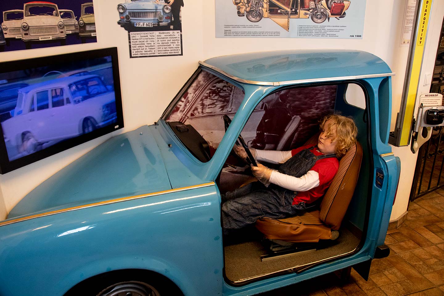 Image of child sitting in the driving seat of a model Trabant car