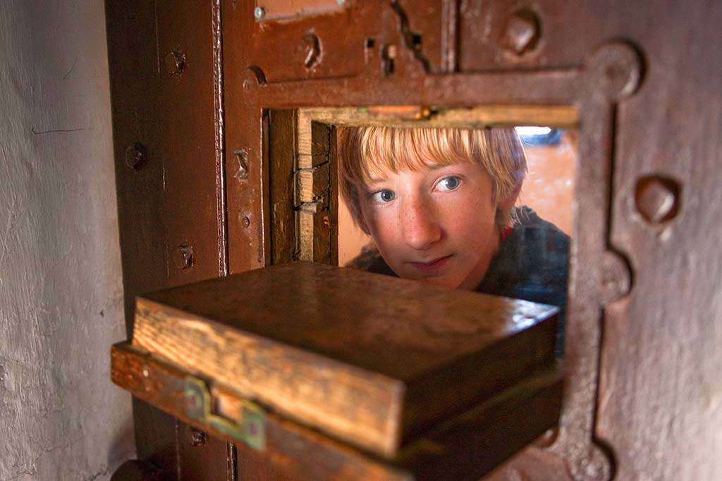 image of boy looking through prison door slot Beaumaris gaol anglesey north Wales uk