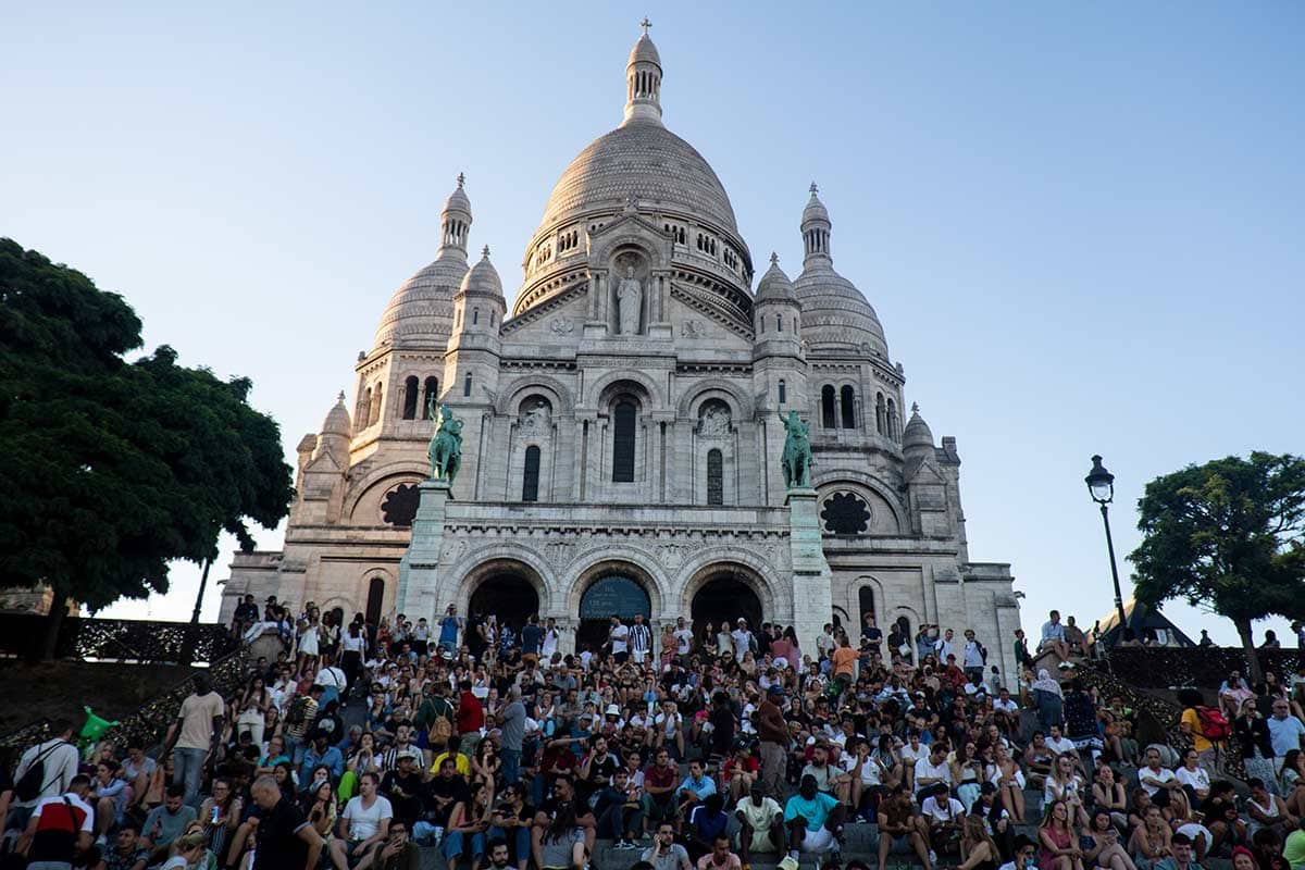 image of people sitting on steps below Sacré coeur basilica Montmartre Paris france