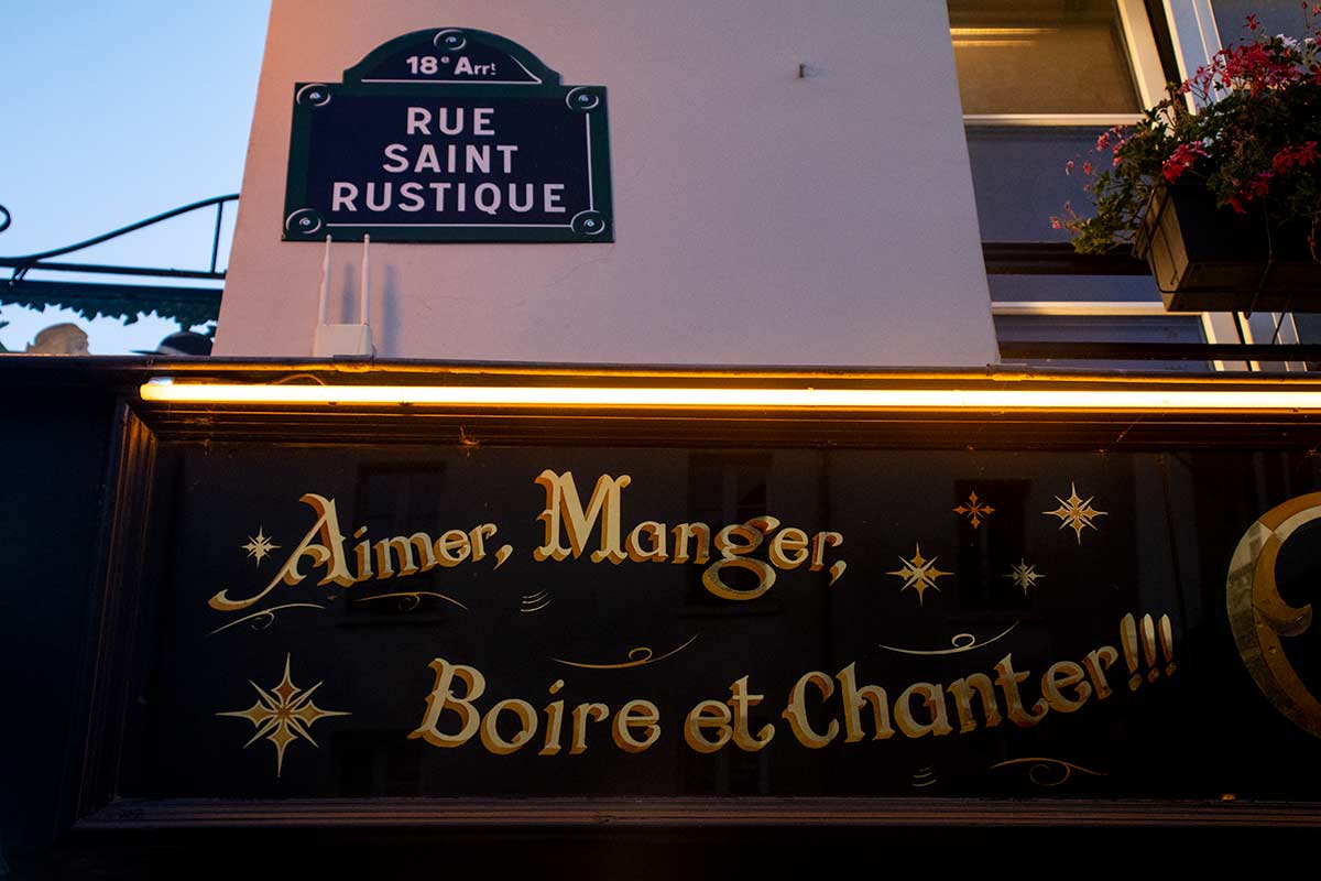 image of rue st rustique street sign above restaurant sign Montmartre Paris france