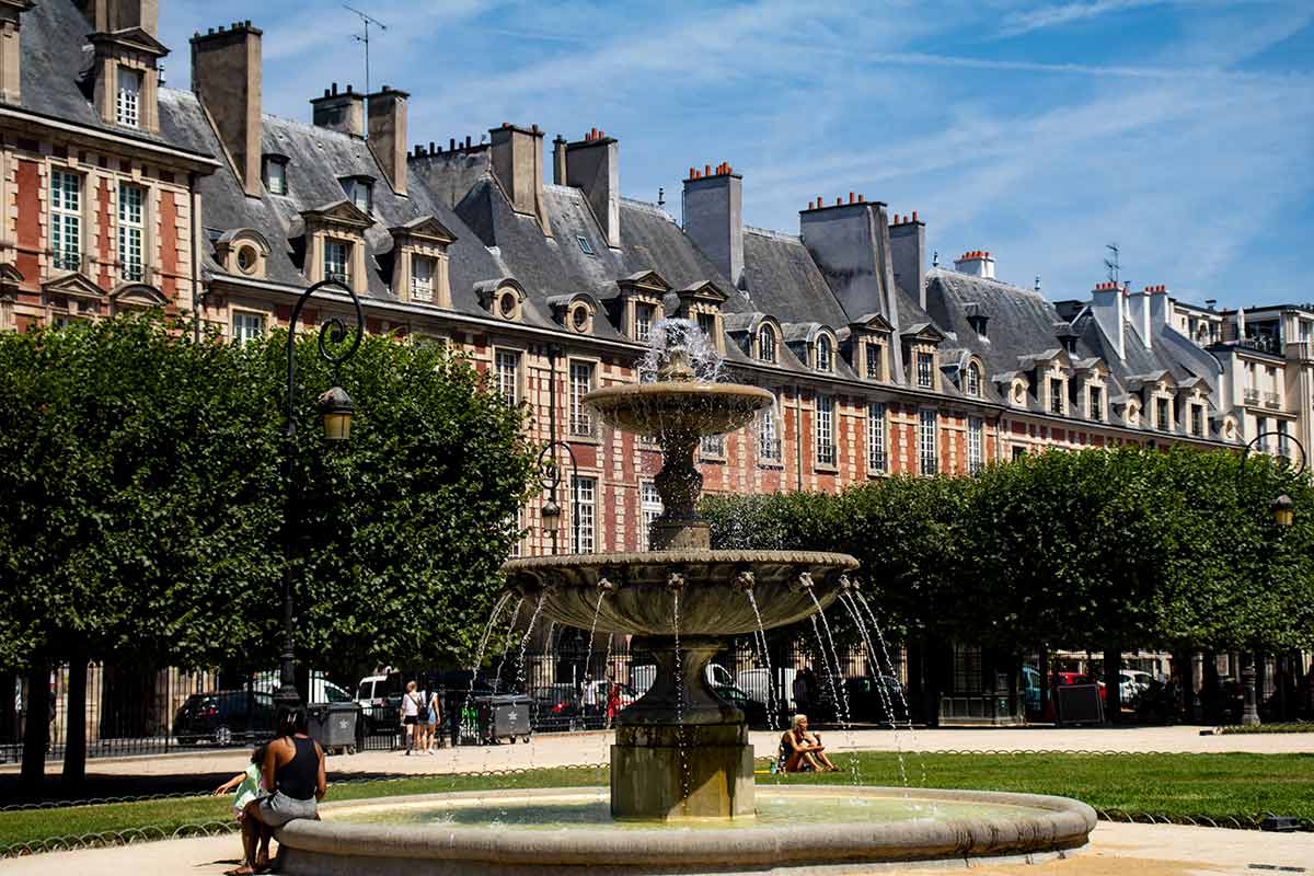 image of fountain and gardens in place des vosges Paris france